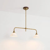 A brass pendant light with two pale alabaster shades casts warm pools of light against a plain white wall.