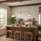A rustic three-light bar pendant fixture with white glass shades hangs over a wooden kitchen island with three woven-back bar stools in a bright, shiplap-walled dining space.