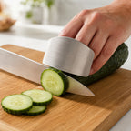 Stainless steel finger guard held against a cucumber while the knife blade rides along the steel face