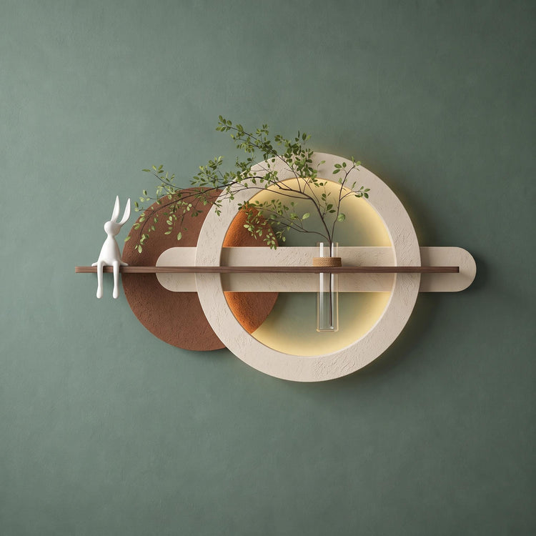 Backlit plaster ring wall art on a sage green wall with a walnut shelf and glass bud vase