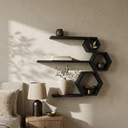 Matte black hexagon and ledge shelves above a bedside table with a lamp