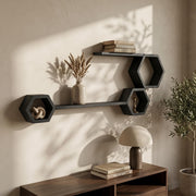 Matte black hexagon and ledge shelves above a dark wood console with dried grasses