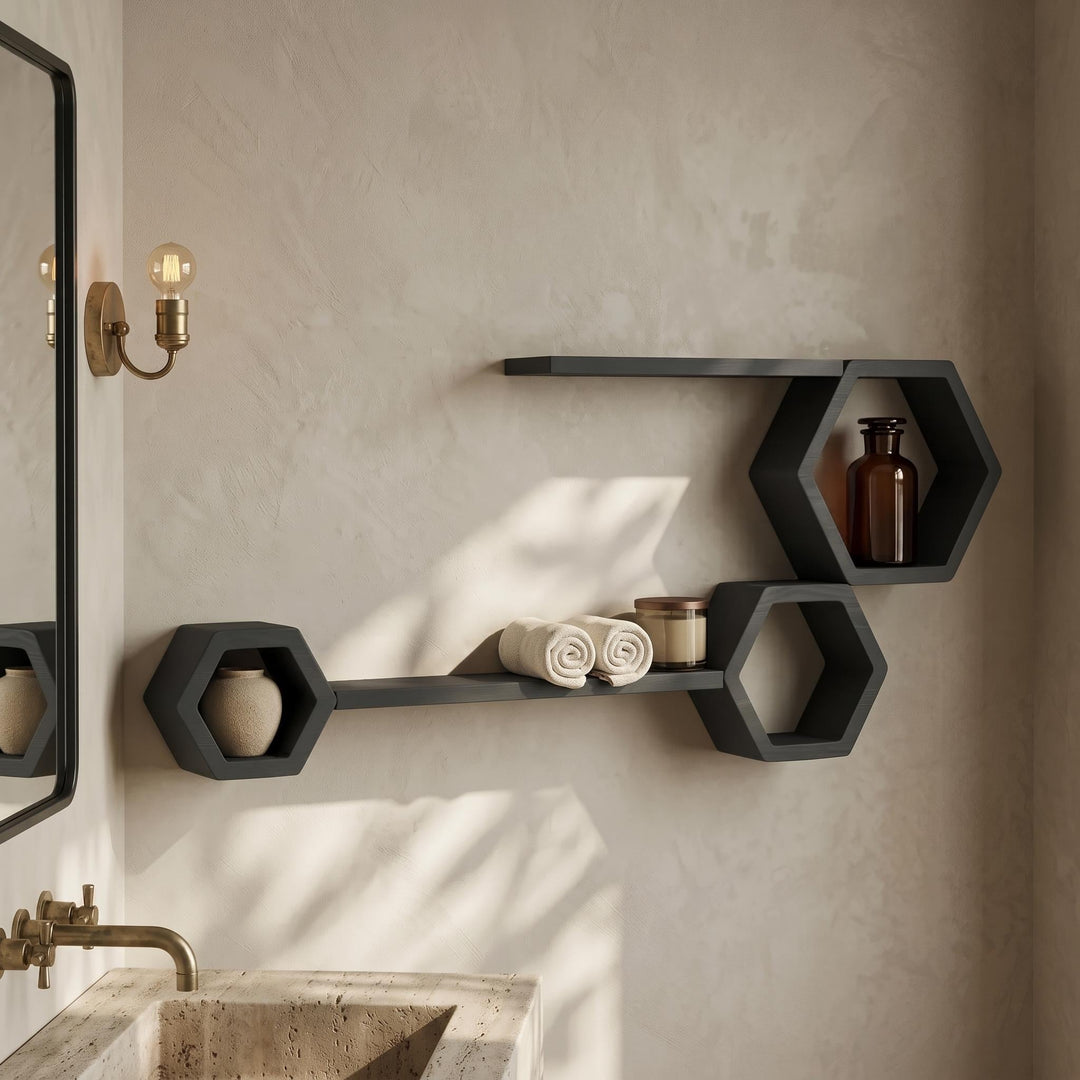 Black hexagon and ledge shelves on a bathroom wall beside a mirror and brass taps