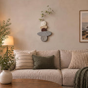 Stacked pebble wall art above a sofa with cushions in a warm neutral room