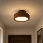 Wood flush mount ceiling light installed in a hallway, warm light on