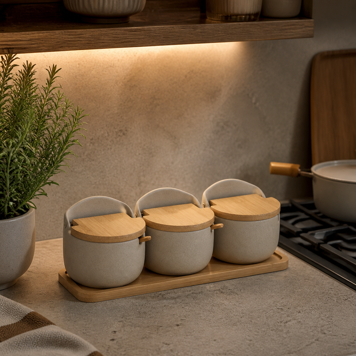 Three ceramic seasoning jars on a bamboo tray in a warm kitchen counter scene