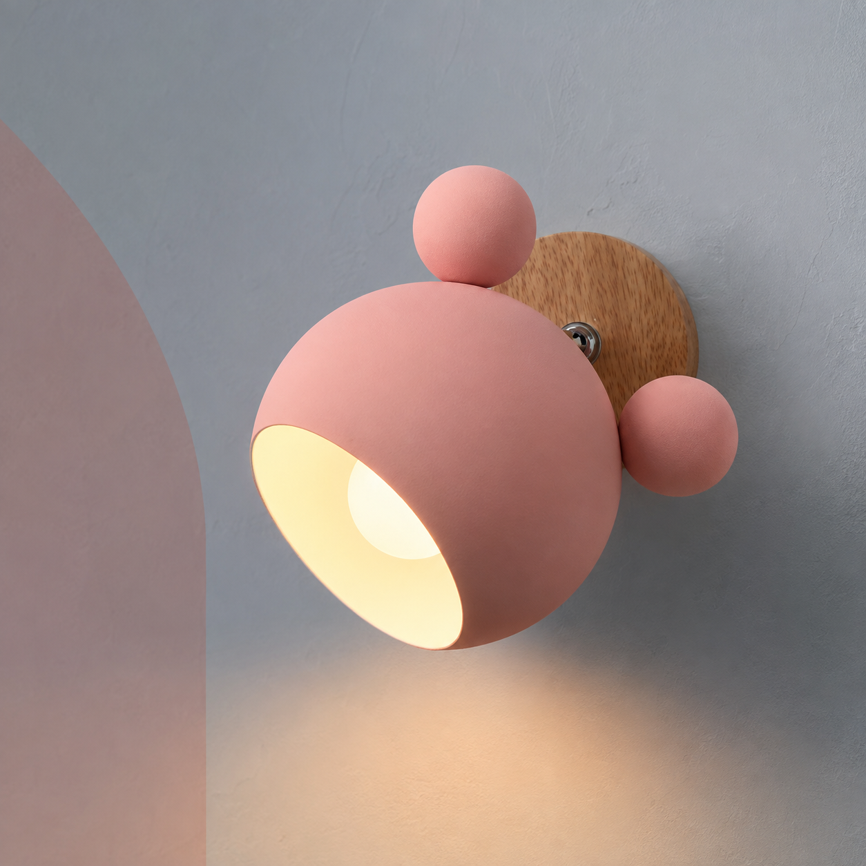 Pink bear nursery wall sconce switched on, warm glow on a blue-gray wall with blush arch