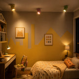 Yellow pink and green adjustable ceiling spotlights glowing in a bedroom
