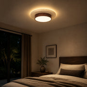 Walnut travertine flush mount ceiling light glowing in a bedroom at night