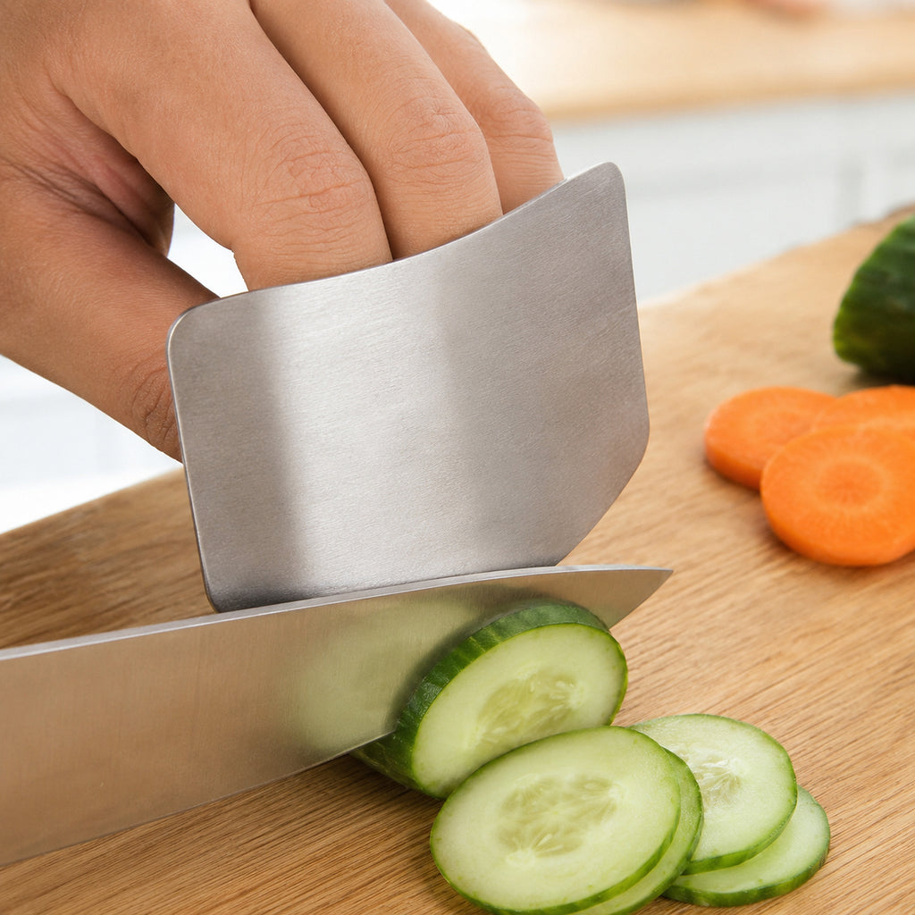 Stainless steel finger guard shielding the fingertips as a chef knife slices cucumber on a wooden board