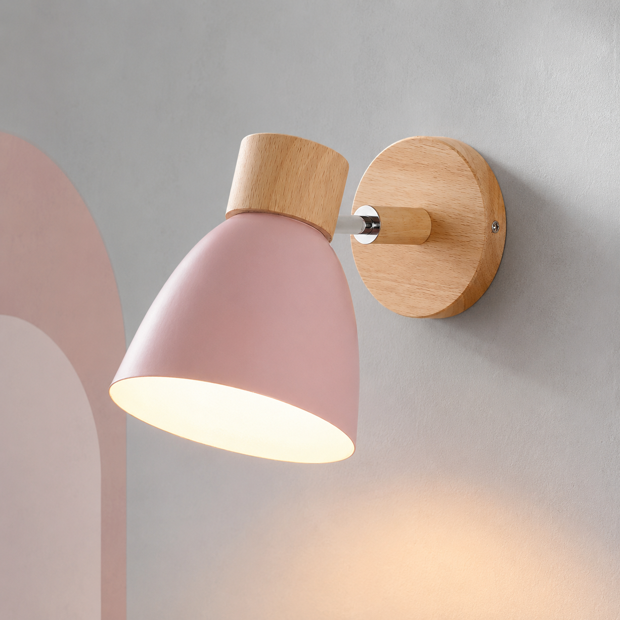 Pink bell bedside wall sconce lit warm on a gray wall with blush arch