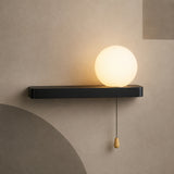 Matte black bar globe wall sconce lit warm with pull chain switch