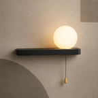 Matte black bar globe wall sconce lit warm with pull chain switch