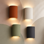 All four fluted resin up down wall sconces lit on a pastel color-block wall