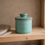 Green reactive glaze butter crock on an open kitchen shelf