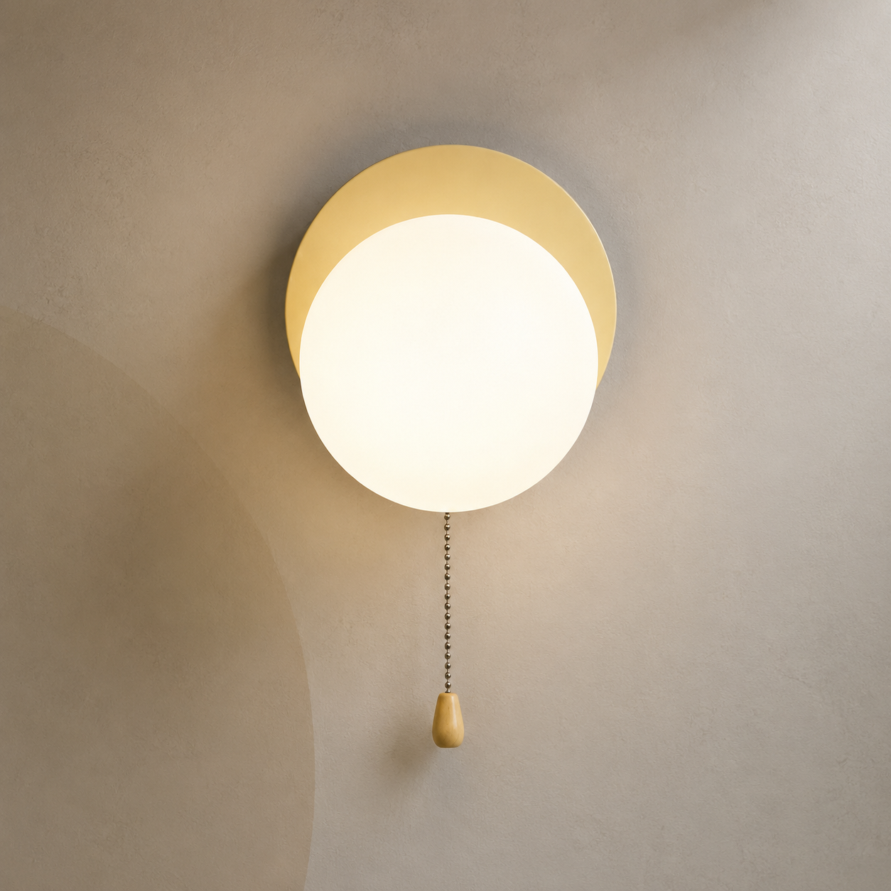 Soft beige disc globe wall sconce lit warm with pull chain switch