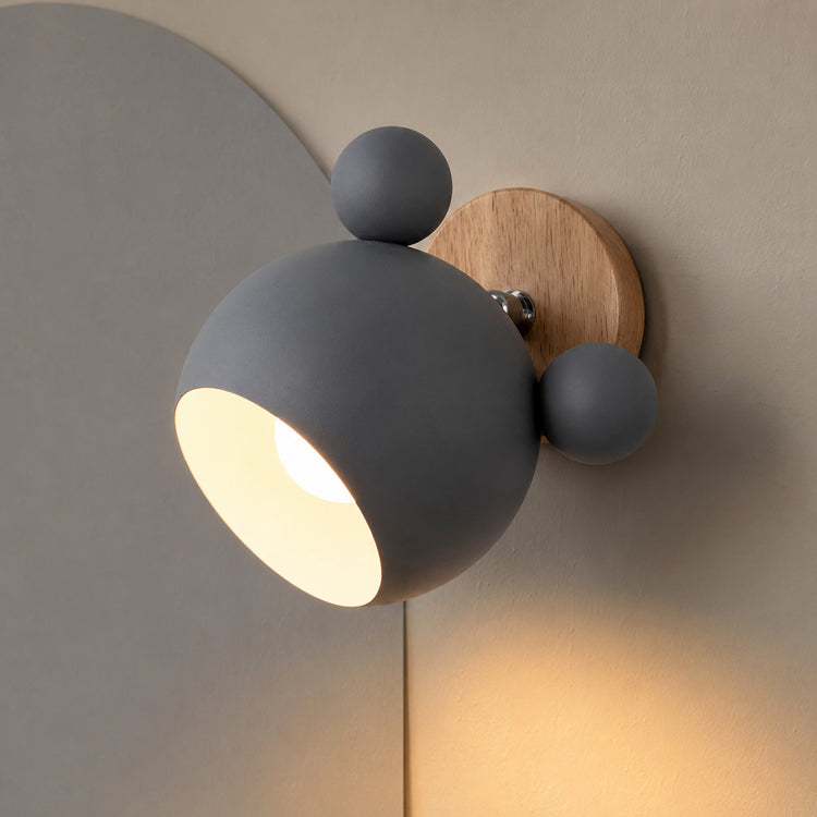 Gray adjustable wall lamp glowing warm on a mushroom wall with soft gray arch