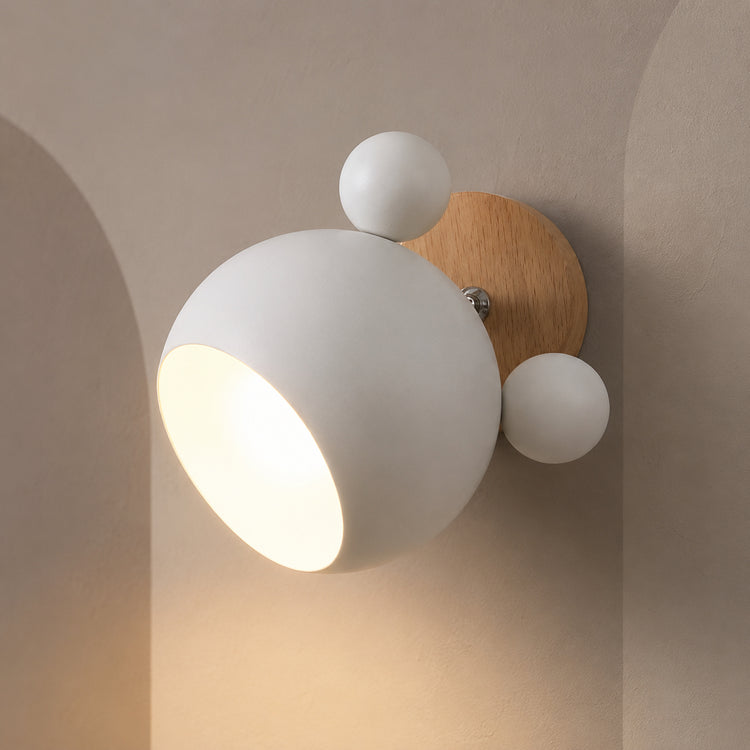 White wall lamp with wood mount lit warm on a greige wall with pale arches