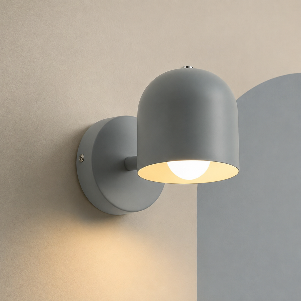 Gray dome wall sconce lit on a cream wall with soft arch