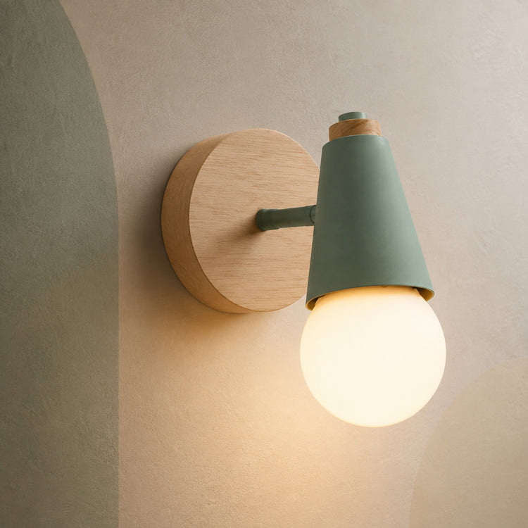 Green wall sconce with rubberwood backplate lit on a sage-tinted wall