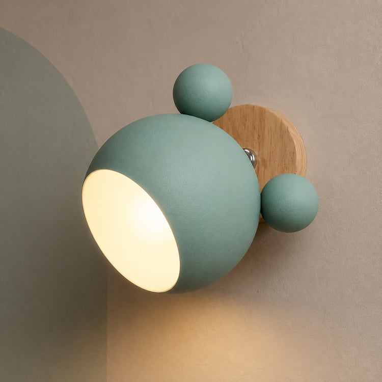 Green bear ear wall light glowing warm on a clay-gray wall with sage arch
