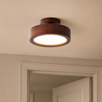 Wood flush mount ceiling light near a door frame, switched on warm glow
