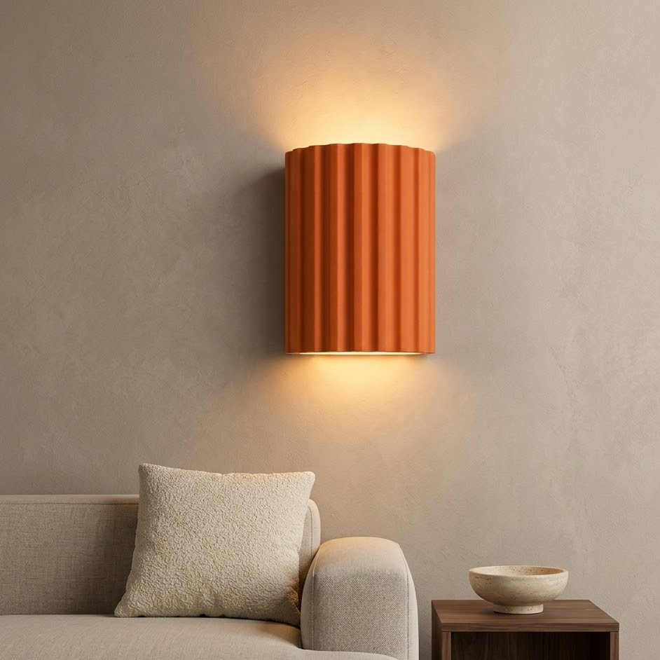 Terracotta fluted wall sconce lit above a linen sofa in a calm living room