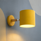 Yellow cylinder wall sconce on wood arm lit on a slate wall
