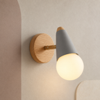 Gray wall sconce with rubberwood backplate lit on a taupe wall