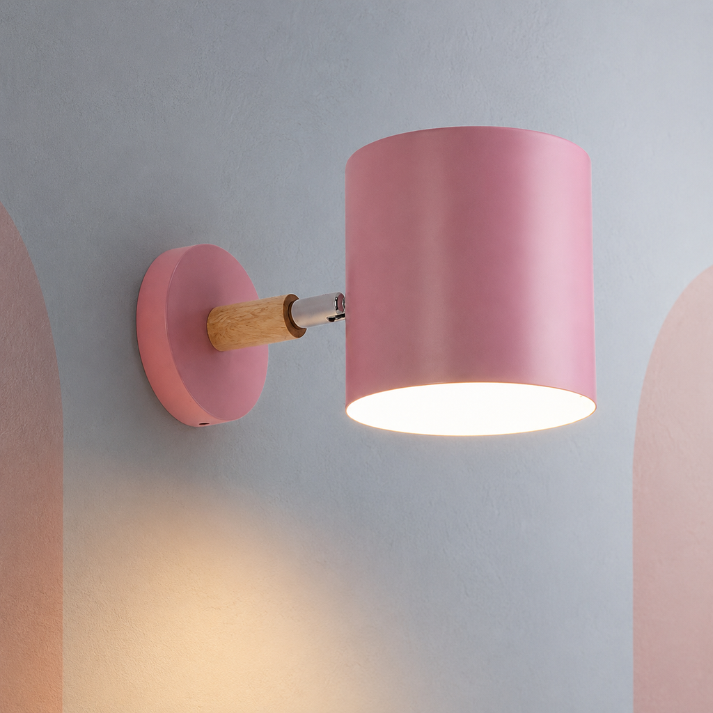 Pink cylinder wall lamp lit warm on a gray wall with blush arches