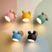 Five lit macaron colors of the bear nursery wall sconce glowing warm on a pastel color-block wall