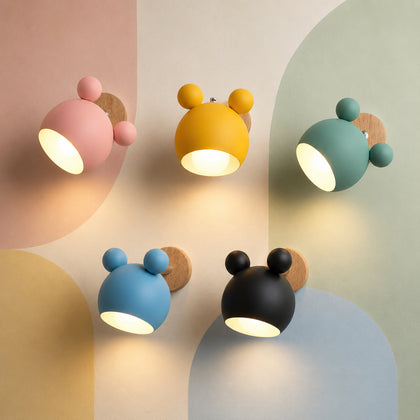 Five lit macaron colors of the bear nursery wall sconce glowing warm on a pastel color-block wall