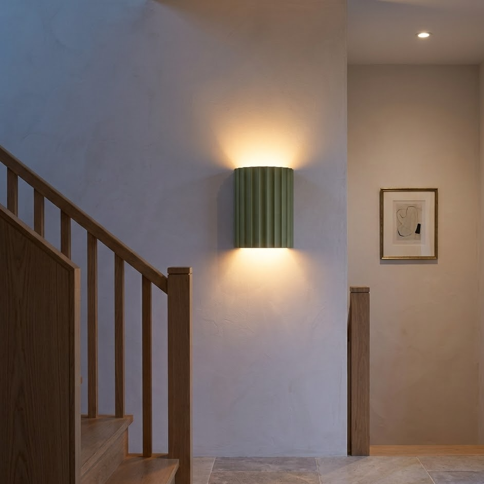 Olive green fluted wall sconce washing light up a stair landing wall