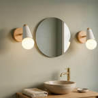 Two white globe vanity sconces with wood backplates flanking a round bathroom mirror