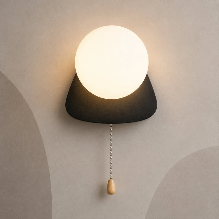 Matte black pebble globe wall sconce lit warm with pull chain switch