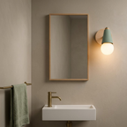 Green globe wall sconce beside a mirror above a wall hung basin in a powder room