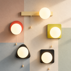 Five lit globe wall sconces with pull chains in bar disc square and pebble shapes on a pastel color-block wall