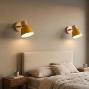 Pair of yellow bell macaron wall sconces flanking a bed above walnut nightstands