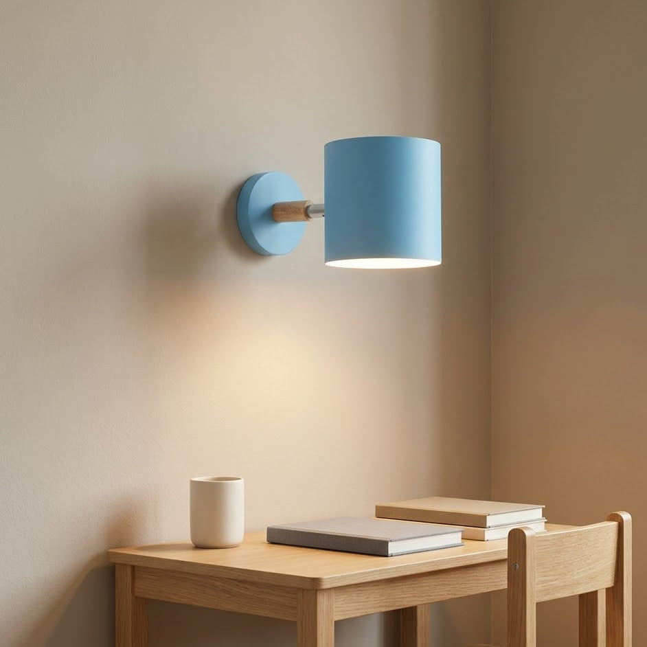 Blue cylinder wall sconce lit above a light oak homework desk in a kids room