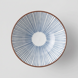 A ceramic bowl with a blue and white striped pattern and a brown rim, resting on a wooden cutting board against a light blue background.