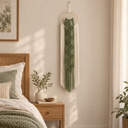 Tall narrow leaf wall hanging in a bedroom corner beside a rattan bed
