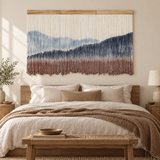 Wide dip dye mountain wall hanging centered above a bed with a wooden bench