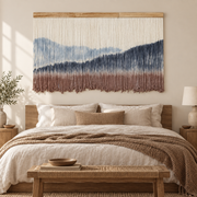 Wide dip dye mountain wall hanging centered above a bed with a wooden bench