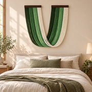 Green U swag fringe wall hanging above a bed headboard in a warm bedroom