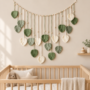 Macrame leaf garland swagged above a wooden cot in a neutral boho nursery