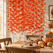 Maple leaf garland curtain behind a Thanksgiving table set with pumpkins