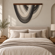 Charcoal arc fringe wall hanging centered above a bed in a minimal bedroom