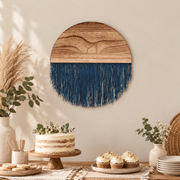 Wood and fringe circle hung above a cake and cupcake table with pampas grass