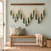 Sage and cream tassel wall hanging above a wooden bench by an entry door