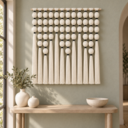 Textured sphere wall hanging above an entryway console with pale ceramic vases